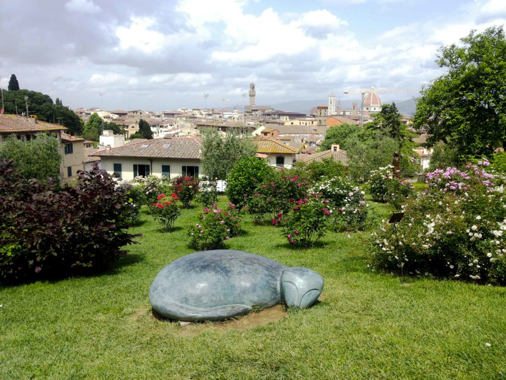 roses garden with cat sculpture and view of the city