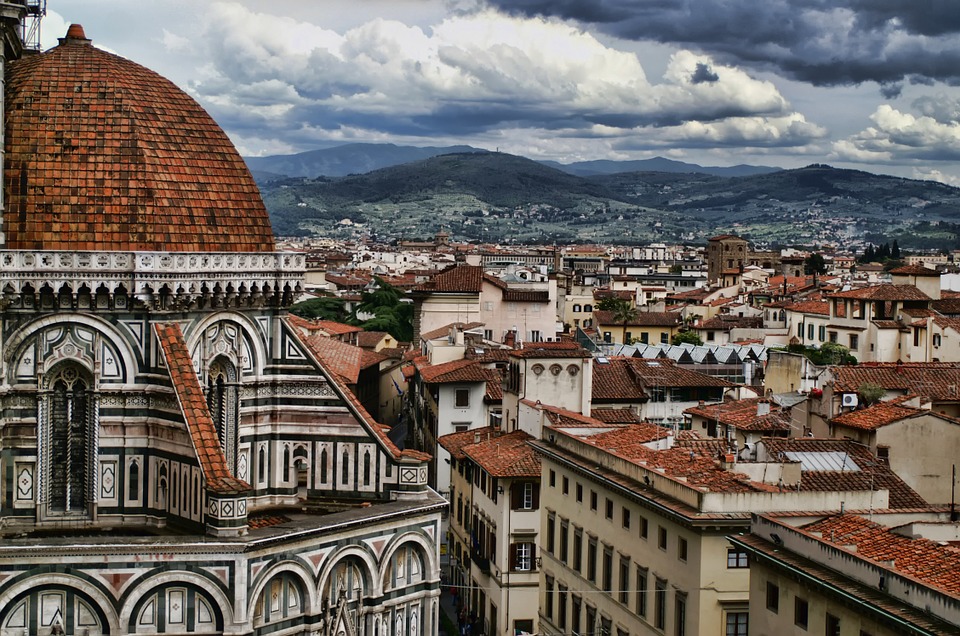 view of the duomo from the belltower of florence, with rooftops and hills in the background