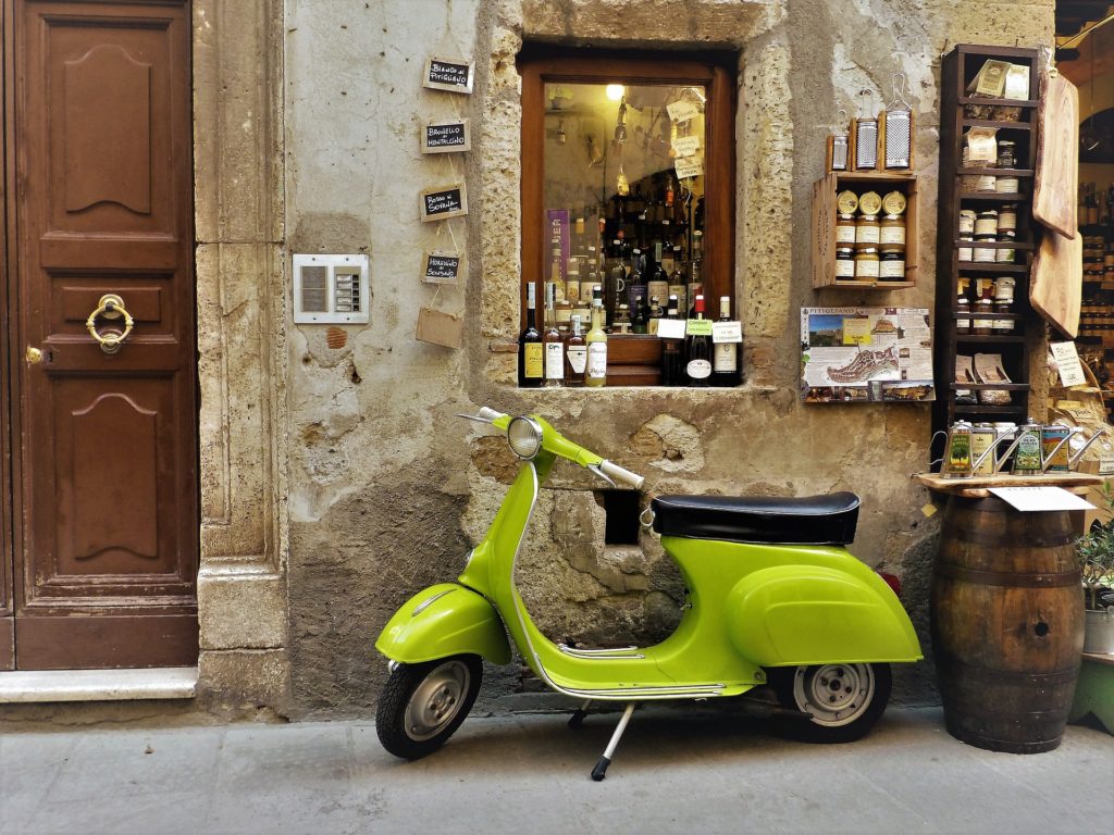 green vintage vespa scooter in a traditional tuscan village