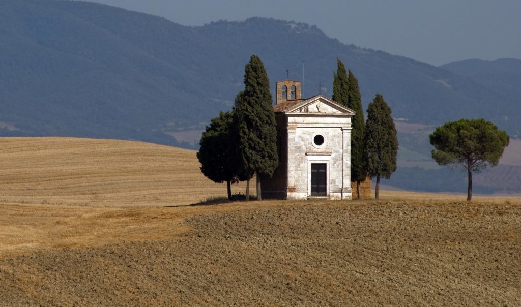 the Vitaleta chapel in Val d'Orcia, surrounded by rolling hills of Tuscany and cypress trees