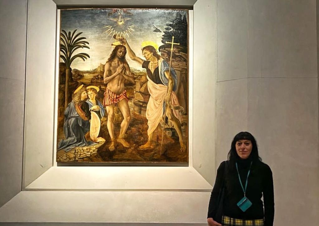 tour guide in front of Leonardo da Vinci and Verrocchio painting of the baptism of Jesus