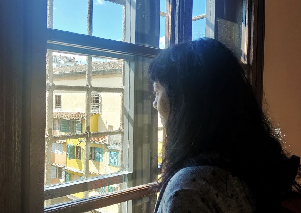 A girl looking out of window facing Ponte Vecchio in Florence